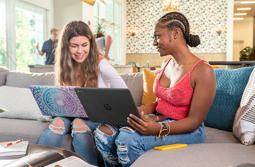 2 Women sitting next to each other on laptops